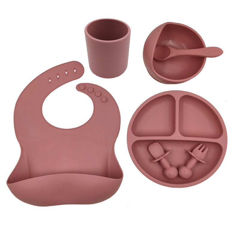 Cozy Cub baby feeding set with silicone bib, cup, and spoon, designed for young children, in bright orange.